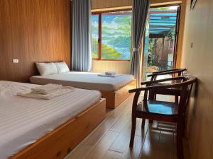 a room with two beds and a chair and a window at Ngan Nga Legend in Bắc Hà
