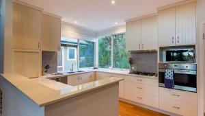 a kitchen with white cabinets and a large window at Sky View - Elevated Estate with Resort-Style Pool in Yallingup