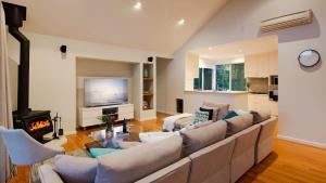 a living room with a large couch and a television at Sky View - Elevated Estate with Resort-Style Pool in Yallingup