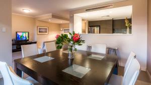 a dining room table with white chairs and a vase of flowers at Surfside 8 - Spacious Retreat on Yallingup Beach in Yallingup