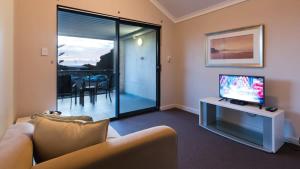 a living room with a couch and a flat screen tv at Surfside 8 - Spacious Retreat on Yallingup Beach in Yallingup