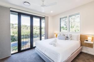 a bedroom with a white bed and large windows at Yallingup Lagoon Beach House in Yallingup