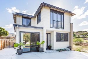 a white house with black windows and potted plants at Yallingup Lagoon Beach House in Yallingup