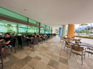 a restaurant with people sitting at tables and chairs at Porto Beach Resort - Marulhos in Porto De Galinhas