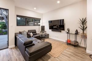 a living room with a couch and a flat screen tv at Rabbits Break - Beachside Bliss Steps from Yallingup in Yallingup