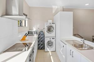 a white kitchen with a washer and dryer in it at Surfside 3A - Vibrant Yallingup Beachfront Living in Yallingup