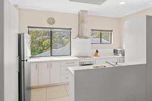a kitchen with white cabinets and a refrigerator at Surfside 3A - Vibrant Yallingup Beachfront Living in Yallingup +5 photos