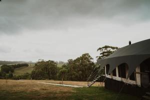 a building with a tent on the side of a field at Wandagar Eco Tent - Carnaby in Pemberton