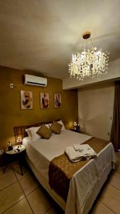 a bedroom with a large bed and a chandelier at Charme do Dido in Ilha de Boipeba