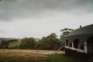 a building with a tent next to a field at Wandagar Eco Tent - Baudin in Pemberton
