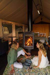 a man and woman sitting in front of a fireplace at Wandagar Eco Tent - Baudin in Pemberton