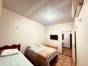 a bedroom with two beds and a tv on the wall at Pousada e Hostel das Rosas in Barreirinhas