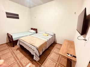 a bedroom with a bed and a flat screen tv at Pousada e Hostel das Rosas in Barreirinhas