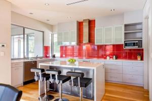 a kitchen with red cabinets and a island with stools at Valley Views - Elevated Hilltop Escape near Beaches in Yallingup