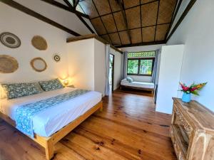 a bedroom with a large bed and wooden floors at Fare Tihi Moana in Tahu-Naoe
