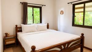 a bedroom with a bed with white sheets and a window at Zen Harmony Pool Villa in Ko Phangan
