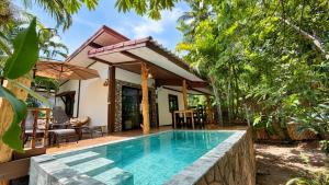 a villa with a swimming pool in front of a house at Zen Harmony Pool Villa in Ko Phangan