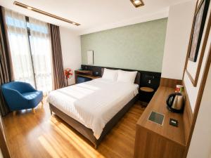 a hotel room with a bed and a blue chair at Ngan Hoa - Mille Fleurs 02 in Da Lat