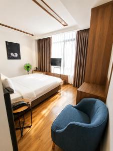a bedroom with a bed and a blue chair at Ngan Hoa - Mille Fleurs 02 in Da Lat