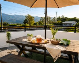 a picnic table on a balcony with an umbrella at 若家民宿 台東縣民宿1275號 in Guanshan