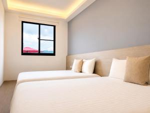 two beds in a room with a window at 若家民宿 台東縣民宿1275號 in Guanshan