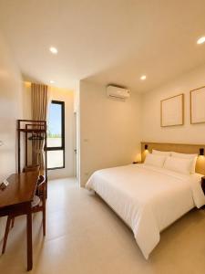 a bedroom with a large white bed and a desk at Tim Kanya Pranburi in Pran Buri