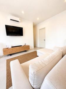a living room with white furniture and a flat screen tv at Tim Kanya Pranburi in Pran Buri