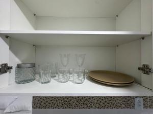 a shelf with glasses and a plate on it at Studio Blanc - Espaço e conforto com uma vista incrivel in Barbacena