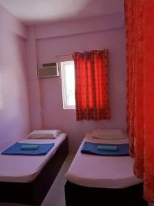 two beds in a small room with a window at Walk Inn Dipolog City by RedDoorz in Dipolog +18 photos