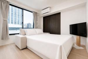 a white bedroom with a large bed and a flat screen tv at Morikoya Hotel in Tokyo