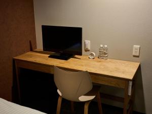 a desk with a computer monitor and a chair at SMART PLACE iNN Hakata-Gion in Fukuoka