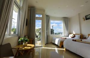 a bedroom with two beds and a table and windows at KS Thanh Thùy in Xuan An