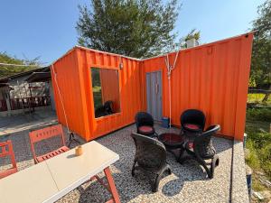an orange shipping container with chairs and a table at Contana Paris in Girijati