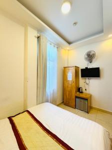 a bedroom with a white bed and a television at KS Thanh Thùy in Xuan An