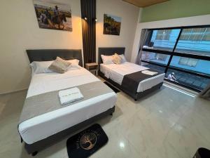 two beds in a room with a window at Hotel del Parque Arauca in Arauca