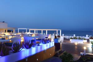 a rooftop patio with tables and chairs at night at Sandos Papagayo in Playa Blanca