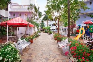 a walkway with benches and flowers and a playground at Avion Holiday Resort in Lonavala