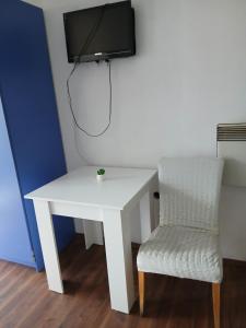 a white desk with a chair and a tv on a wall at Charshija in Struga +2 photos