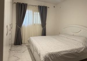 a bedroom with a white bed and a window at Mountain Escape with Rooftop in Jūrat Arşūn