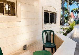 a green chair sitting on the outside of a building at Mountain Escape with Rooftop in Jūrat Arşūn
