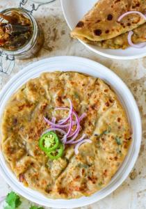 a plate of food with a pizza on a table at The Seven Suites - Fort View in Chittaurgarh