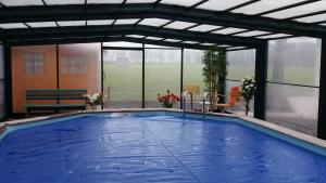 a large swimming pool in a building with a roof at Het Findament Tiny house in Hilversum