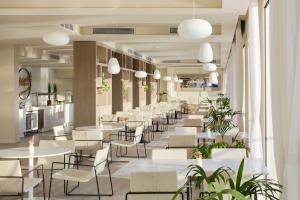 a restaurant with white tables and chairs and plants at Meliá Cala Galdana in Cala Galdana +139 photos