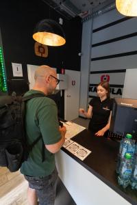 a man with a backpack standing at a counter with a woman at Kapsuła Hostel Warszawa in Warsaw