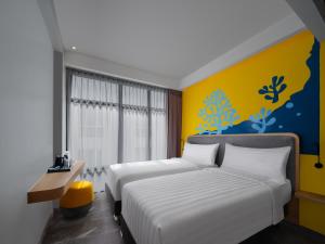 a bedroom with two beds and a yellow wall at Quest Vibe Dewi Sri Bali in Legian +29 photos