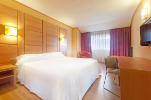 a hotel room with a white bed and a desk at Hotel Puertollano in Puertollano