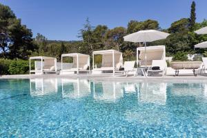 a pool with chairs and umbrellas next to the water at Hotel Eetu Begur, Affiliated by Meliá in Begur