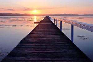 a wooden pier stretches out into the water at sunset at Seaside Haven in Port Welshpool +5 photos
