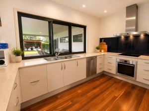 a kitchen with white cabinets and a large window at Bawley Backyard Haven - family retreat near beach in Bawley Point