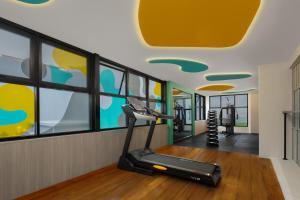 a gym with a treadmill in a room with windows at Quest Vibe Dewi Sri Bali in Legian